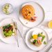A plate of grilled salmon, boiled eggs, fresh spinach and walnuts arranged on a light kitchen counter
